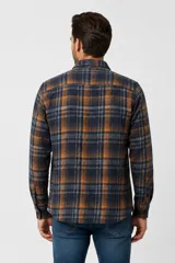 Sobrecamisa de franela a cuadros en tonos marrones, blancos y rojos, con mangas largas, bolsillos frontales con solapa y cierre de botones.