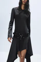 Vestido midi de cuello redondo y manga larga, confeccionado en tejido de punto gris oscuro. Presenta un cinturón integrado con hebilla y aplicación de tachas metálicas, y un bajo con diseño asimétrico y volados.