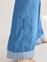 Pantalón jean celeste de corte ancho, con ruedo combinado en un tono más claro.