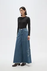 Pantalon de jean negro de corte ancho y tiro alto, con detalle de estrella bordada en la pierna y ruedo deshilachado.