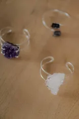 Pulsera abierta de metal plateado con diseño minimalista de doble aro, engarzada con una piedra natural en bruto.