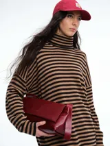 Polera de tejido de punto con diseño de rayas horizontales en tonos marrón y negro, cuello alto, mangas largas con hombros caídos y corte holgado.