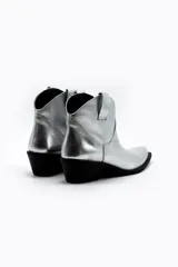 Botas de cuero vacuno color negro con caña baja bordada a tono, tacón bajo, punta alargada redondeada y suela cuadrada.