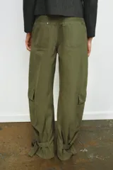 Pantalón cargo de tiro medio confeccionado en algodón, con diseño de pierna ancha y costuras verticales. Presenta bolsillos laterales y bolsillos de plastrón con solapa en las piernas. El bajo es ajustable mediante trabillas y hebillas metálicas.