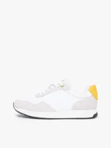Zapatillas de estilo runner de Tommy Hilfiger, confeccionadas en una mezcla de cuero y textil en color blanco con detalles en gris claro y un panel amarillo en el talón. Presentan cordones blancos y suela de goma con base oscura.