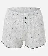 Pijama corto de algodón blanco, compuesto por una remera de manga corta con cuello redondo y estampa frontal de Mafalda durmiendo, y un short con estampa de lunares y detalle de ondas negras en el ruedo.