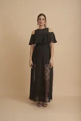 Vestido largo negro con hombros descubiertos, volados en el pecho, mangas cortas y paneles de encaje transparente en la falda.