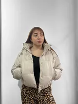 Campera puffer color beige con cuello alto, cierre frontal con cremallera y bolsillos laterales.
