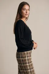 Cardigan negro de algodón con cuello en V, cierre frontal de botones y mangas largas con textura calada. Presenta puños y ruedo acanalados.