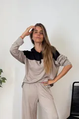 Sudadera tipo canguro con capucha y cordones, de manga larga y corte amplio. Presenta un diseño bicolor: la parte superior (hombros y capucha) es negra, y el resto del cuerpo y mangas son de color beige oscuro/topo.