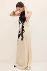 Vestido largo halter confeccionado en poliéster, con diseño bicolor en negro y beige, escote cruzado y detalle bordado de girasol en el frente.