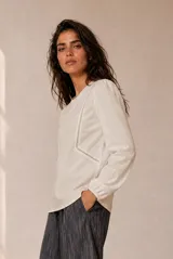 Remera beige de manga larga, con detalles de encaje geométrico en el frente y puños elásticos.