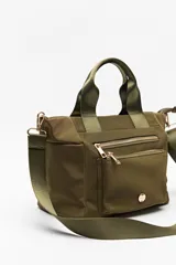 Cartera negra de nylon con diseño compacto y funcional. Cuenta con asas cortas y correa regulable desmontable para llevar al hombro o cruzada, además de múltiples bolsillos con cierre y detalles dorados.