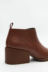 Botín negro de cuero sintético con punta fina, elástico lateral y taco ancho de 6cm.