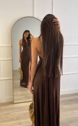 Vestido largo color marrón, con escote profundo en V, cuello halter y falda con tajo lateral. Presenta un diseño drapeado en la cintura.