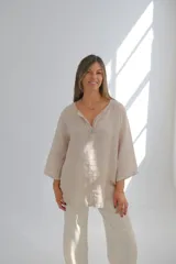 Blusa color crudo de lino con corte holgado, mangas 3/4 y cuello en V con botón.