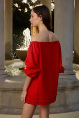 Vestido corto color rojo con hombros descubiertos, mangas largas abullonadas y detalle de volados fruncidos en el ruedo.