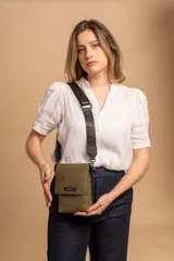 Phonebag pequeña color mostaza, confeccionada en cuero sintético, con solapa frontal y correa ajustable con logo de la marca.