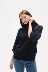 Polera de tejido de punto color gris, con cuello alto, mangas 3/4 y diseño holgado.
