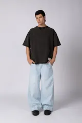 Remeron de corte oversized con cuello redondo y mangas cortas. Presenta un acabado de tela con efecto desgastado y costuras visibles en los bordes, con una etiqueta pequeña en el lateral inferior.