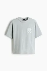 Remera gris melange de punto pesado de algodón, de corte holgado con hombros caídos, cuello redondo acanalado y bajo recto. Cuenta con un diseño estampado en el pecho con las inscripciones 'SOHONYC' y '86'.