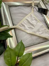 Pack de tres tangas de algodón con tiras laterales regulables. El conjunto incluye una prenda negra, una blanca y una color champagne.