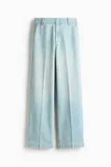 Jean de denim de algodón rígido color celeste claro, de tiro alto y corte recto holgado. Presenta bolsillos al bies y pliegues marcados adelante y atrás.