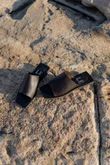Sandalias planas de diseño minimalista con punta cuadrada, confeccionadas en cuero color marrón oscuro con suela negra.