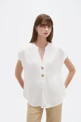 Blusa de viscosa color blanco, de corte holgado, con cuello en V y cierre frontal parcial de botones grandes con efecto carey.