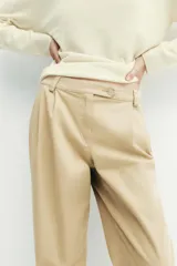 Pantalón chino de tiro medio, corte recto y holgado, con pinzas en la parte delantera. Presenta bolsillos laterales, falsos bolsillos traseros con solapa y bajo con dobladillo vuelto. Cierre frontal con cremallera y botones.