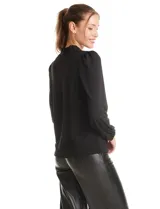 Blusa de seda fría color negro, con escote en V y lazo decorativo al cuello. Presenta mangas largas abullonadas con puños elásticos y detalles de strass aplicados en cuello, lazo y mangas.