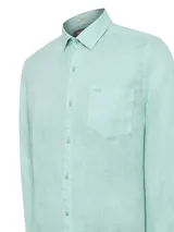 Camisa de manga larga confeccionada en lino orgánico, color verde menta. Presenta cuello clásico, cierre frontal con botones, bolsillo en el pecho con logo bordado y espalda de jersey ligero.