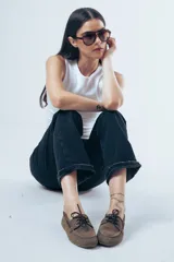 Mocasín de estilo náutico confeccionado en cuero gamuzado color tostado, con cordones decorativos laterales y en el empeine.