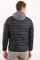 Campera capitoneada color azul marino, con capucha de algodón gris desmontable y cierre frontal. Tiene dos bolsillos exteriores con cierre.