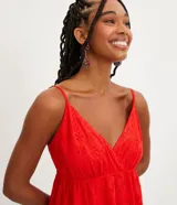 Vestido corto rojo con breteles finos ajustables, escote en pico, textura de flores y volado en el bajo.