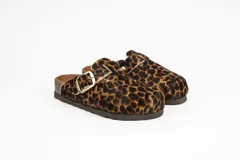 Zueco de cuero con estampa tipo animal print de vaca, con tira de ajuste marrón y hebilla metálica. Plantilla anatómica y suela de corcho y goma.