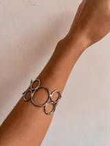 Brazalete plateado con diseño de círculos y líneas, hecho a mano en alpaca.