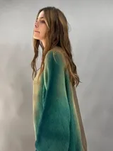 Buzo tejido de lana merino con diseño oversize, manga ranglan y cuello levemente elevado. Presenta un efecto de teñido degradado que combina tonos verdes y beige.