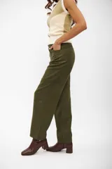 Pantalon de corte recto y tiro alto en color verde oliva, confeccionado en tejido con textura similar a la gamuza. Presenta costuras horizontales a la altura de las rodillas y cierre frontal con botón oculto.