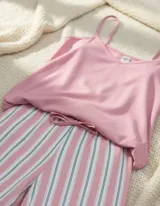 Pijama compuesto por una musculosa rosa de breteles finos y un pantalón a rayas verticales en tonos rosados, blancos y oscuros, con lazo ajustable en la cintura.
