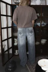 Jean de corte recto y tiro medio, con costuras verticales decorativas en el frente y bordado de brújula en los bolsillos traseros.