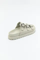 Sandalia negra tipo slide con plataforma gruesa y tres tiras ajustables con hebillas metálicas plateadas. La capellada es de material con textura de gamuza o nobuck.