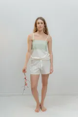 Pijama de dos piezas, compuesto por una musculosa blanca con detalle de puntilla negra elástica en el escote y un short blanco con elástico y lazo negro en la cintura.
