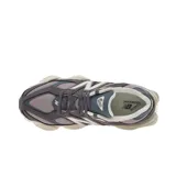 Championes urbanos New Balance modelo 9060, color gris con detalles en crema y azul oscuro. Presentan un diseño futurista con líneas onduladas, entresuela esculpida con tecnología ABZORB y una combinación de materiales premium en la capellada.