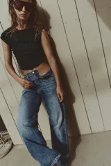 Jeans de tiro medio con diseño de cinco bolsillos, pernera recta y corte cropped. Presenta cierre frontal con cremallera y botón metálico.