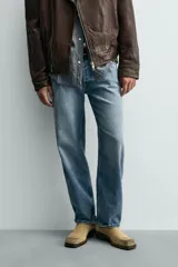 Pantalón de jean con corte recto desde la cadera hasta el tobillo, de tiro medio y ajuste holgado. Presenta diseño de cinco bolsillos, cierre frontal con cremallera y botón, y acabado con efecto lavado.