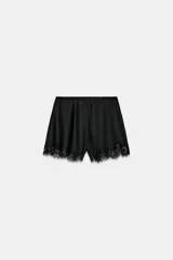 Shorts negro de tiro alto, confeccionado en tejido satinado, con cintura elástica y detalle de aplicación de encaje negro en el ruedo.
