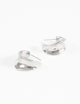 Par de aros tipo argolla de plata, con forma curva y textura martillada o pulida irregular.