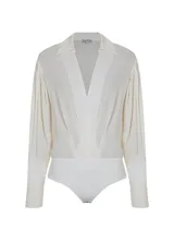 Body color crudo con cuello solapa, escote en V, manga larga con botones en los puños y detalles fruncidos.