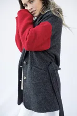 Tapado de paño de lana con diseño bicolor, cuerpo en color gris oscuro y mangas en color rojo. Presenta cierre frontal con botones y lazo ajustable en la cintura.